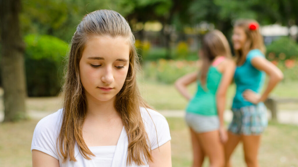 Mujer pensativa junto a una ventana en un día soleado de primavera, reflejando el contraste emocional que puede surgir en esta estación.