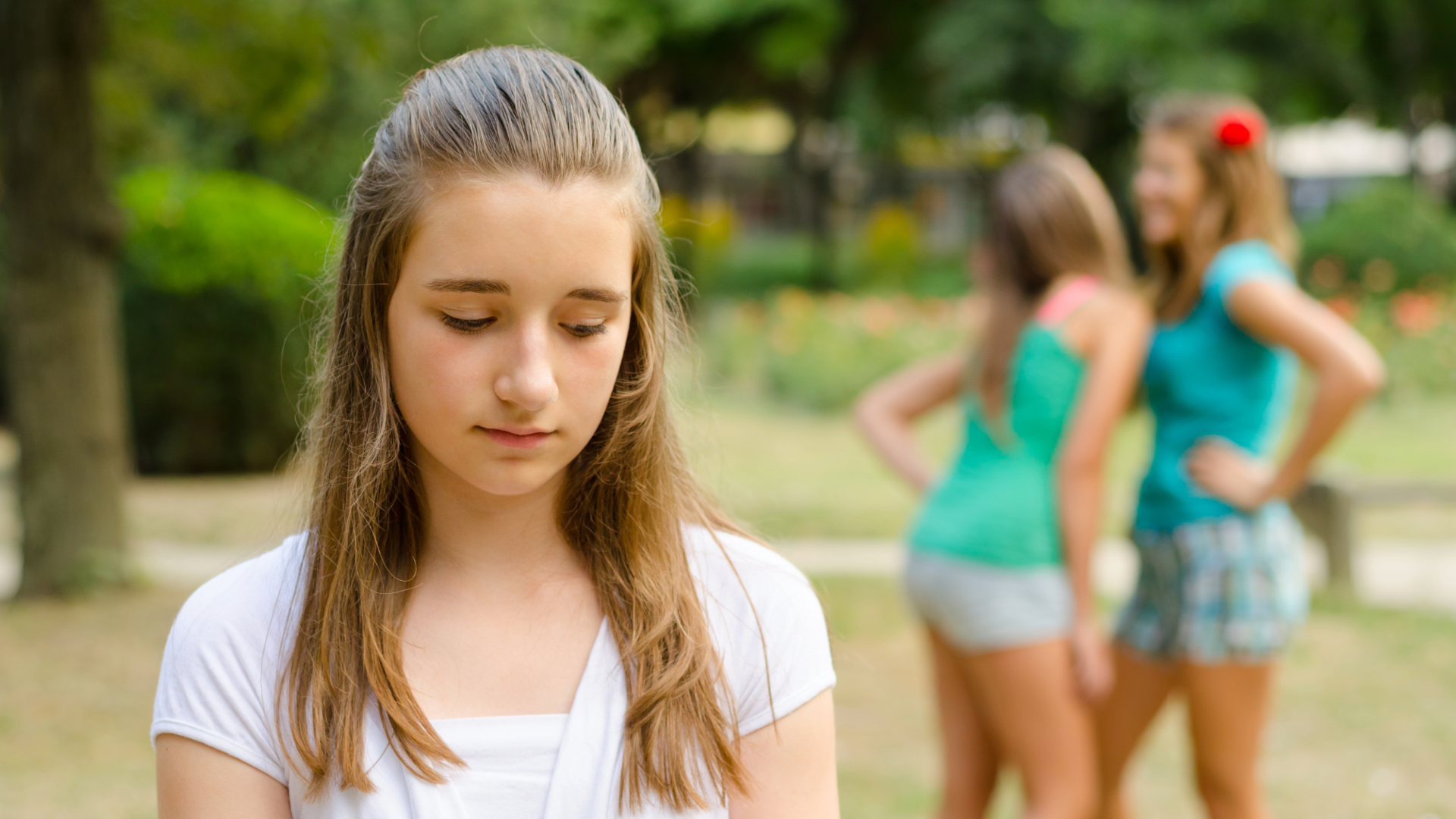 Mujer pensativa junto a una ventana en un día soleado de primavera, reflejando el contraste emocional que puede surgir en esta estación.